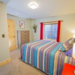 bedroom with Red curtains and purple, blue, and yellow stripped bedding