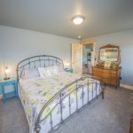 View of Metal Bed with Yellow Floral bedspread, light blue night stands, and warm wood furniture