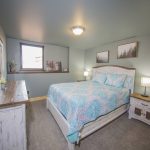 Bedroom with Light blue bedspread and art of foggy pines
