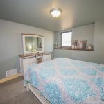 Bedroom with Light blue bedding and white washed dresser and mirror