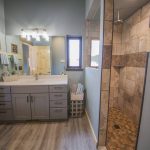 stone tile shower with waterfall shower head and bathroom vanity